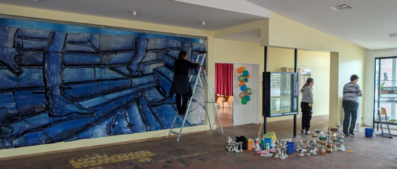 Eltern und Kinder reinigen Vitrinen und Kunstwerke im Foyer